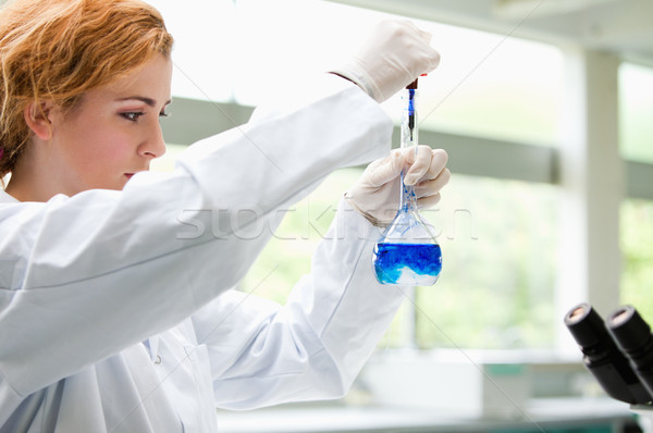 Cute science student putting blue drops in a liquid in a laboratory Stock photo © wavebreak_media