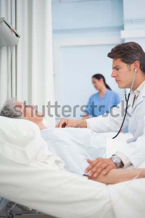 Patient lying on a bed next to a doctor and a nurse in hospital ward Stock photo © wavebreak_media