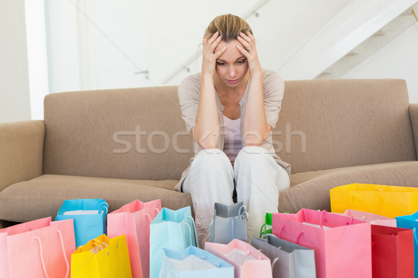 Regretful woman looking at many shopping bags on the couch Stock photo © wavebreak_media