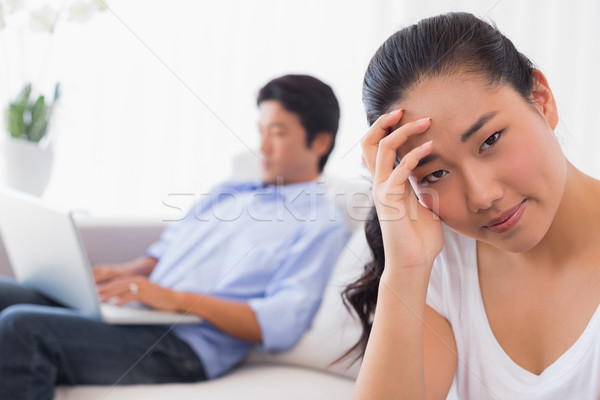 Upset woman sitting on couch while boyfriend uses laptop Stock photo © wavebreak_media