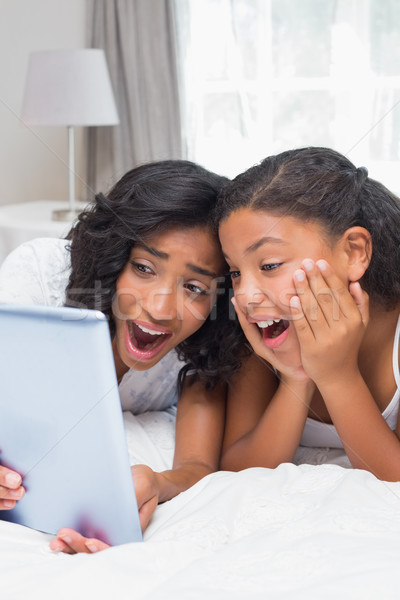Surprised mother and daughter using tablet together Stock photo © wavebreak_media