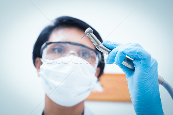 Female dentist in surgical mask holding dental drill Stock photo © wavebreak_media