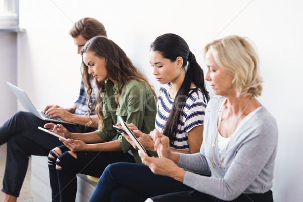 Stock photo: Business people using technologies while sitting on seat