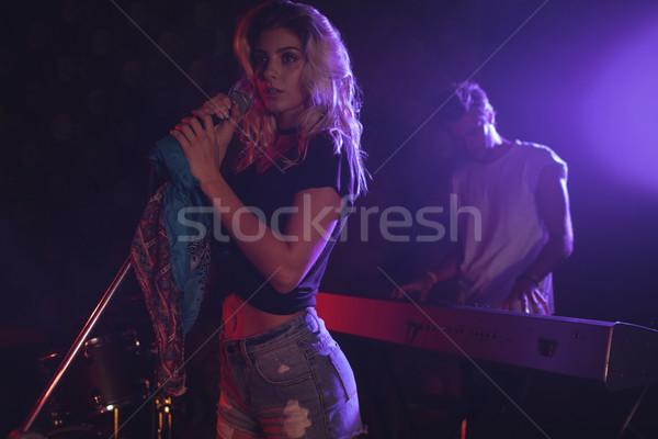 Female singer performing while coworker playing piano in illuminated nightclub Stock photo © wavebreak_media