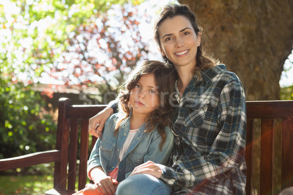 Portrait of smiling beautiful woman sitting with daughter on wooden bench Stock photo © wavebreak_media