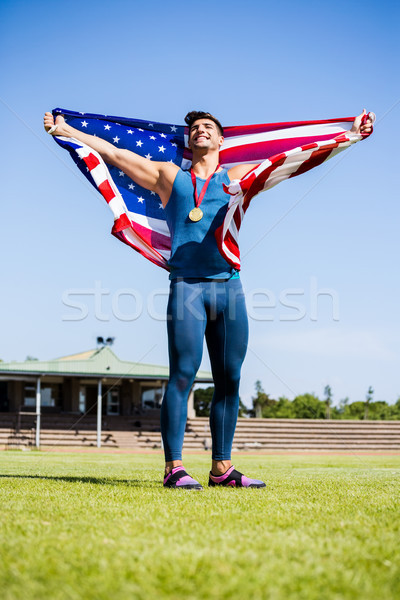 Sportowiec stwarzające amerykańską flagę złota około Zdjęcia stock © wavebreak_media