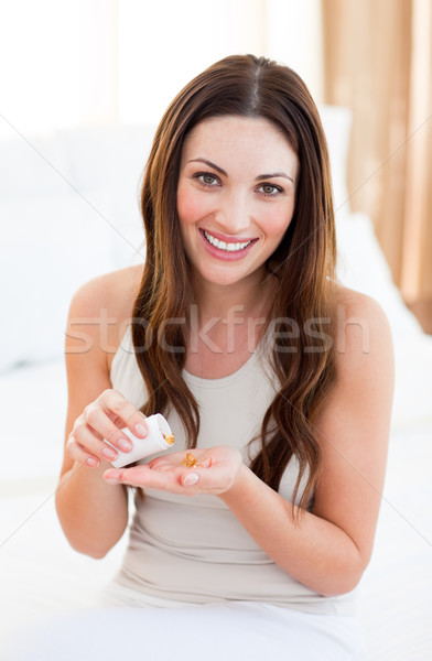 Mujer bonita toma píldora sesión cama casa Foto stock © wavebreak_media