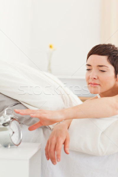 Cute brunette turning off her alarm clock in her bedroom Stock photo © wavebreak_media