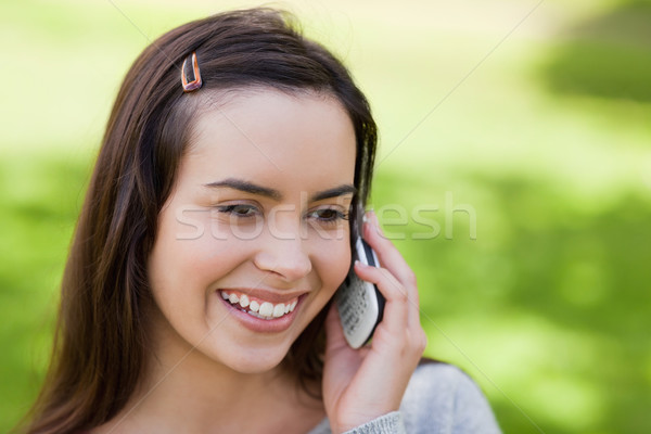 Smiling young woman using her mobile phone while standing in a parkland Stock photo © wavebreak_media
