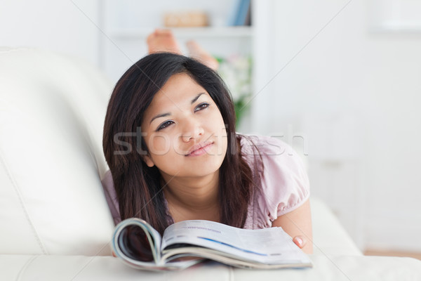 Stock photo: Woman lays on a sofa while reading a magazine in a living room