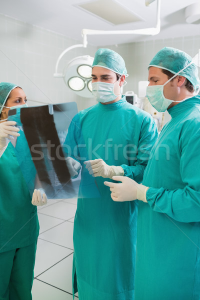 Stock photo: Close up of a surgical team examining a X-ray in an operating theatre