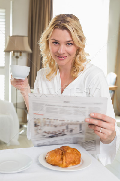 Pretty blonde in bathrobe drinking coffee and reading newspaper Stock photo © wavebreak_media