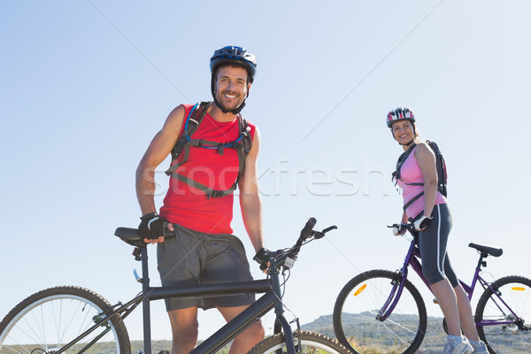 Fit cyclist couple standing at the summit smiling at camera Stock photo © wavebreak_media