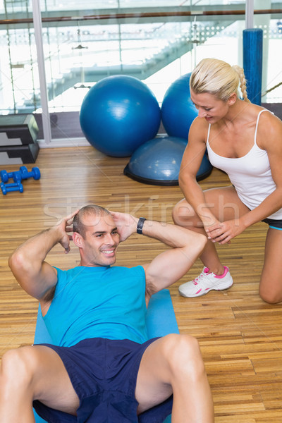 Stock photo: Trainer assisting man with abdominal crunches at fitness studio
