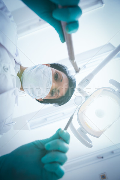 Female dentist in surgical mask holding dental tools Stock photo © wavebreak_media