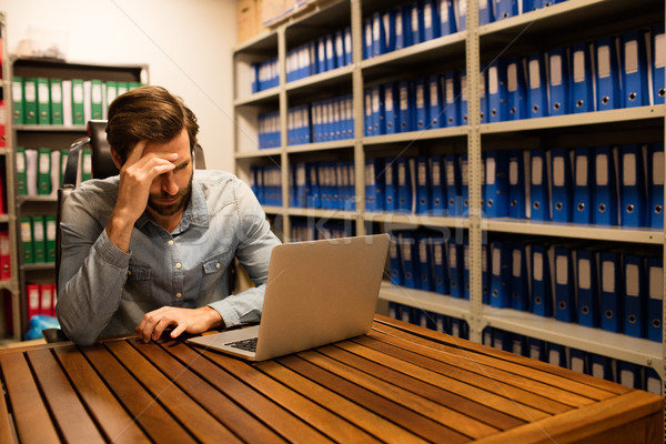 Tensed business executive using laptop in file storage room  Stock photo © wavebreak_media