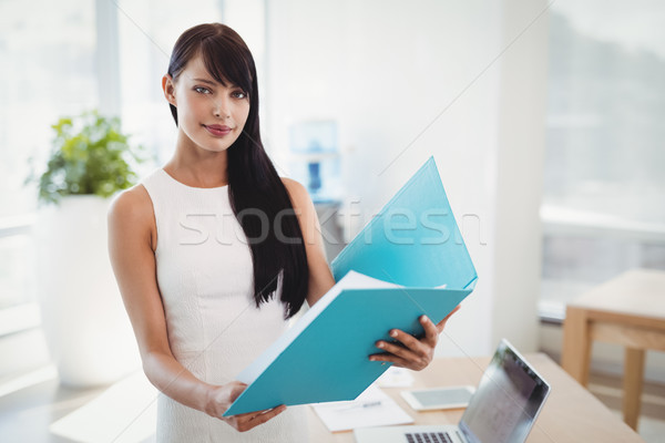 Portrait of beautiful executive holding file at desk Stock photo © wavebreak_media