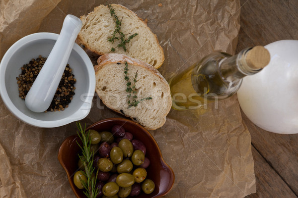 Directly above shot of olives with oil bottle and bread by spices in mortar pestle on crumbled paper Stock photo © wavebreak_media