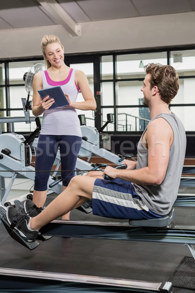Trainer writing on a clipboard while man exercising on a rowing  Stock photo © wavebreak_media