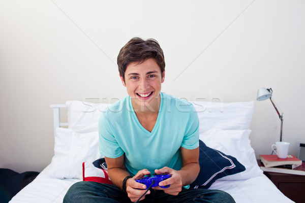 Stock photo: Happy teenager playing video games in his bedroom