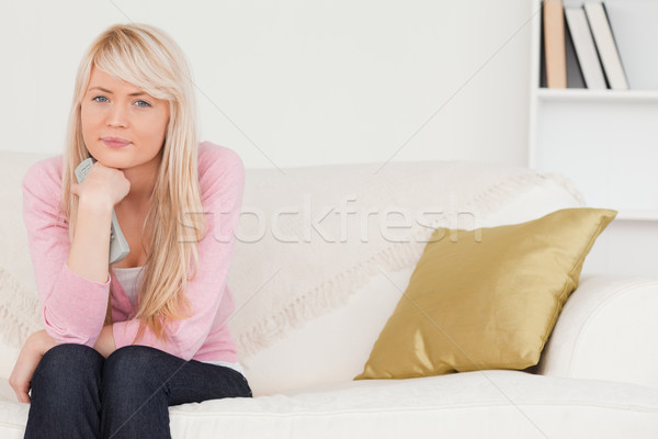 Beautiful blonde female posing while sitting on a sofa in the living room Stock photo © wavebreak_media