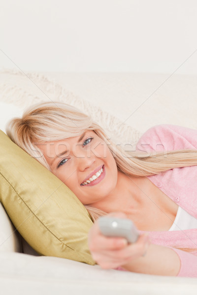 Beautiful blonde female posing while lying on a sofa in the living room Stock photo © wavebreak_media