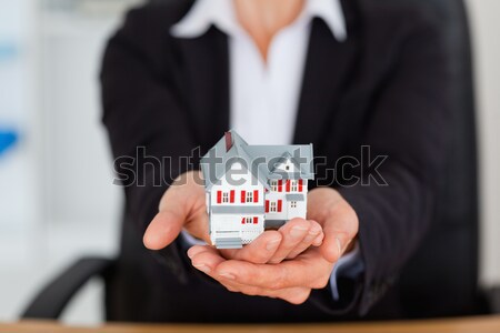 Portrait of feminine hands holding a miniature house in an office Stock photo © wavebreak_media