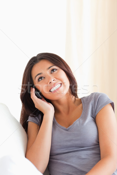 dark-haired woman phoning looking at the ceiling in livingroom Stock photo © wavebreak_media