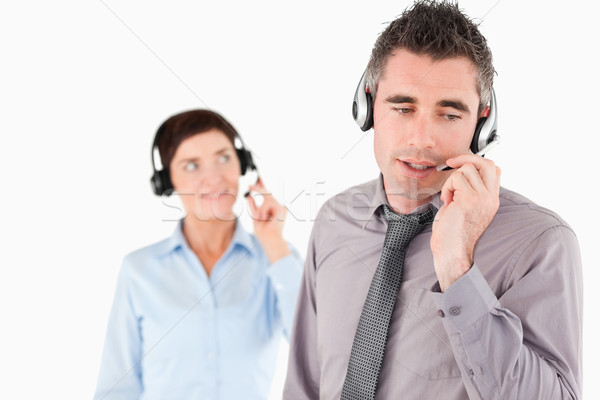 Stock photo: Office workers speaking through headsets against a white background
