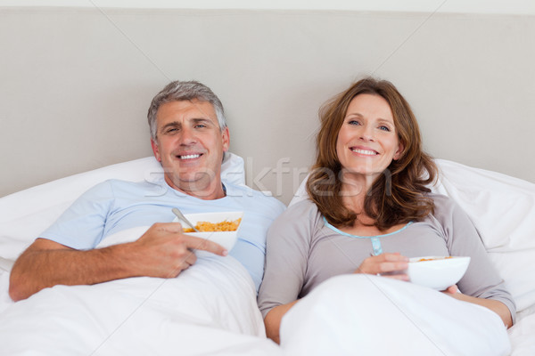Stock photo: Mature couple eating cereals in bed