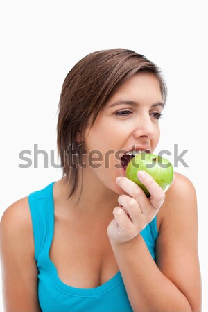 Attractive teenager eating a green apple while looking to the side Stock photo © wavebreak_media