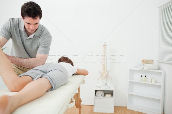 Serious brunette physiotherapist stretching the leg of a patient in a room Stock photo © wavebreak_media