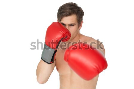 Tough man wearing red boxing gloves punching to camera Stock photo © wavebreak_media