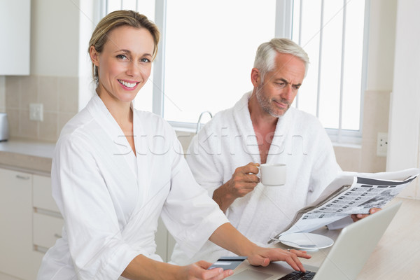Couple shopping online and reading newspaper in bathrobes  Stock photo © wavebreak_media