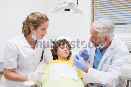 Pediatric dentist showing little boy how to brush teeth with his Stock photo © wavebreak_media