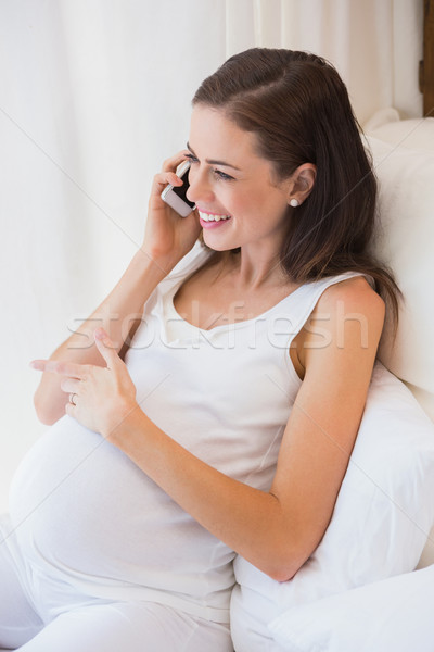 Smiling pregnancy phoning in his bed  Stock photo © wavebreak_media