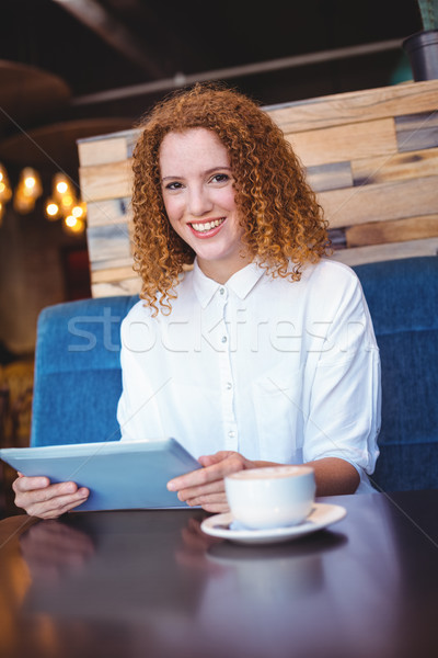 Stock photo: Pretty girl using a small tablet at table