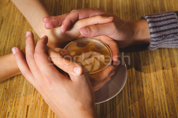 Couple holding hands around cappuccino with coffee art Stock photo © wavebreak_media