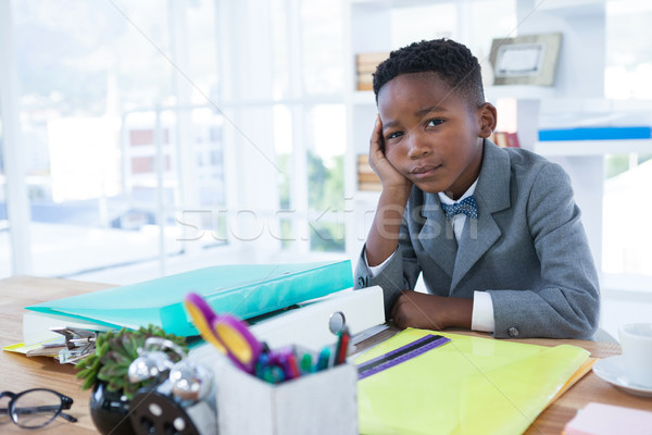 Stock photo: Portrait of businessman with hand on chin sitting at desk