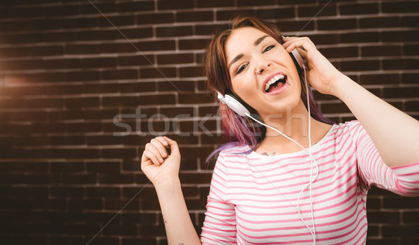 Portrait femme souriante écouter musique casque mur de briques [[stock_photo]] © wavebreak_media