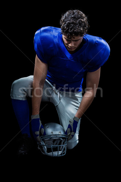 Stock photo: American football player looking down while holding helmet