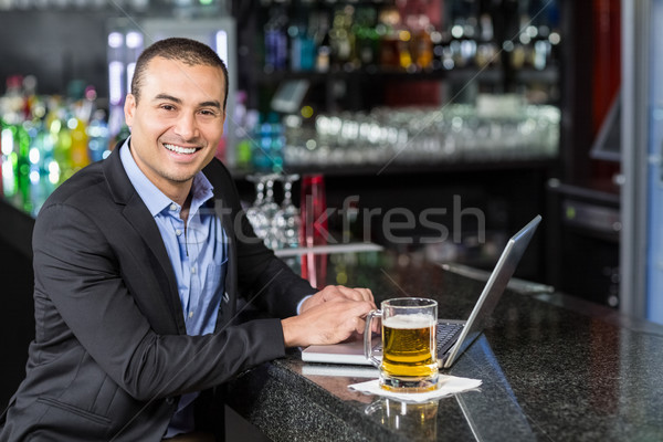 Glimlachend zakenman met behulp van laptop bar gelukkig bier Stockfoto © wavebreak_media
