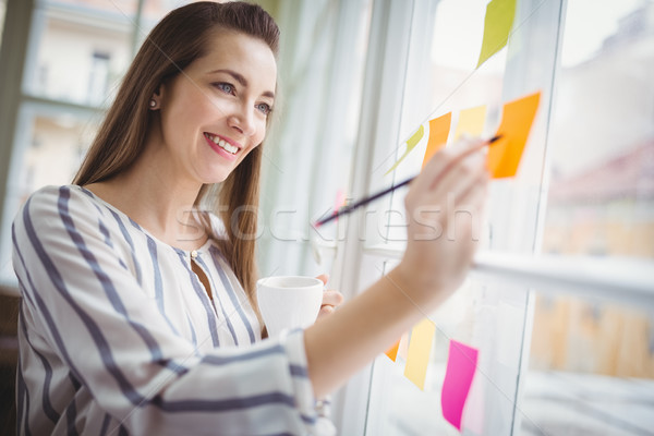 Stock photo: Businesswoman writing on adhesive notes in creative office