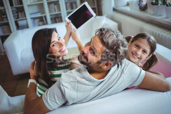 Parents sitting on sofa with daughter and clicking a selfie on digital tablet Stock photo © wavebreak_media