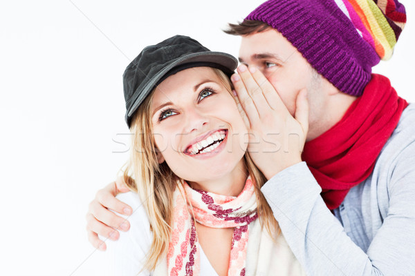 Handsome man with hat telling a secret to his laughing girlfriend against a white background Stock photo © wavebreak_media