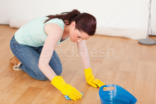 Gorgeous red-haired woman cleaning the floor while kneeling at home Stock photo © wavebreak_media