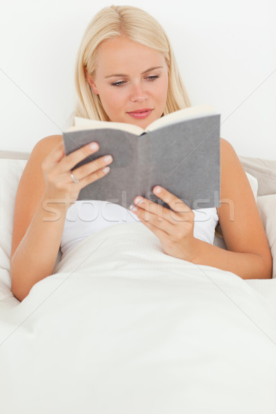 Stock photo: Portrait of a blonde woman reading a book in her bedroom