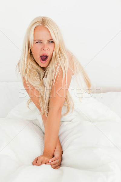 Portrait of a cute woman yawning sitting on her bed Stock photo © wavebreak_media