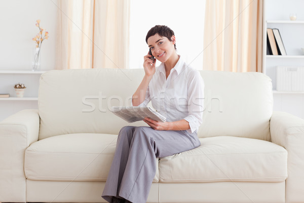 Stok fotoğraf: Güzel · bir · kadın · cep · telefonu · gazete · bakıyor · kamera · oturma · odası