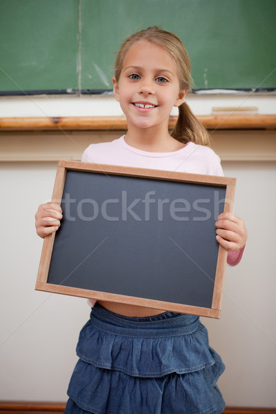 Portrait of a happy girl holding at a school slate in a classroom Stock photo © wavebreak_media